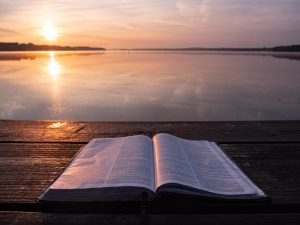 Bible in sunset by water (Which was the first the Bible or the Quran?)